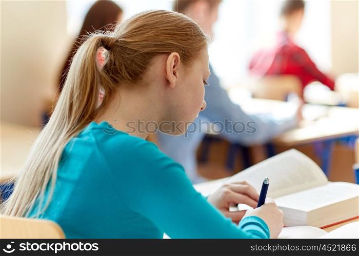 education, learning and people concept - close up of student girl with book writing school test