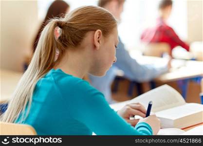 education, learning and people concept - close up of student girl with book writing school test