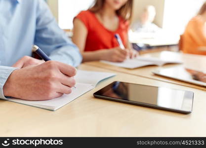 education, learning and people concept - close up of students with notebook and tablet pc computer writing school test