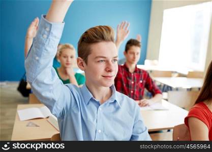 education, learning and people concept - group of students raising hands at school lesson