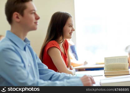 education, learning and people concept - group of students with books and notebooks at school lesson