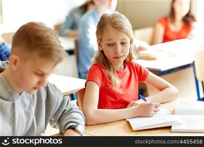 education, learning and people concept - group of students with books writing school test and girl cheating