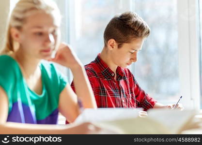 education, learning and people concept - group of students with books writing school test