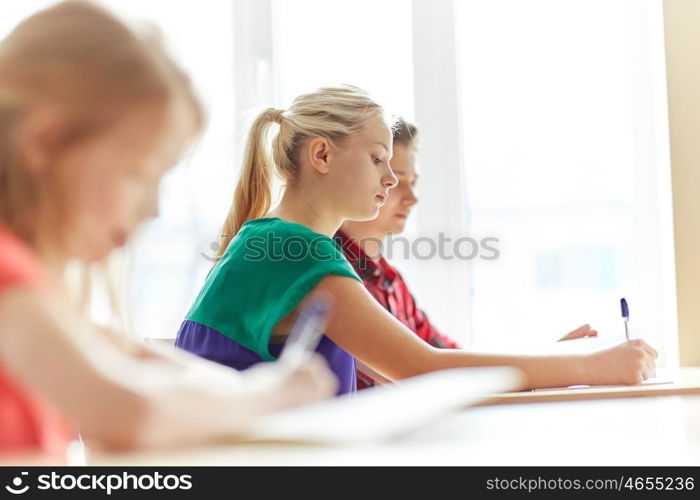 education, learning and people concept - group of students with books writing school test