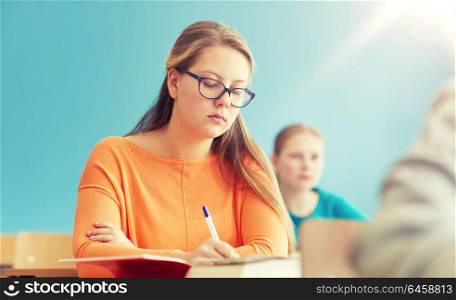 education, learning and people concept - group of students with books writing school test. group of students with books writing school test