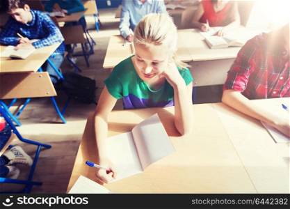 education, learning and people concept - group of students with notebooks and books writing school test. group of students with books writing school test