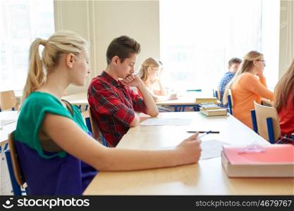 education, learning and people concept - group of students writing school test