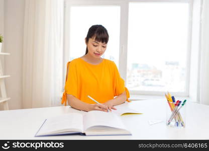 education, learning and people concept - happy asian student girl with book and notebook at home. happy student girl with book and notebook at home