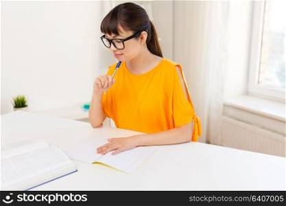 education, learning and people concept - happy asian student girl with book and notebook at home. happy student girl with book and notebook at home