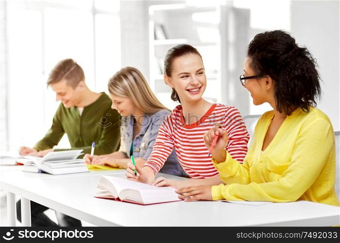 education, learning and people concept - happy high school student girls or classmates with books and notebooks talking. high school students with books and notebooks