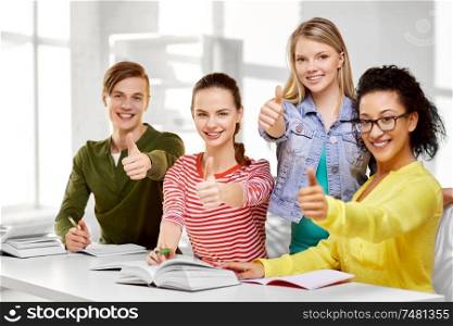 education, learning and people concept - happy high school students or classmates with books and notebooks showing thumbs up. high school students with books and notebooks