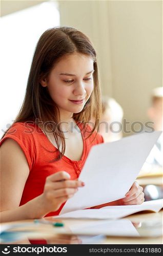 education, learning and people concept - happy student girl with test paper at school