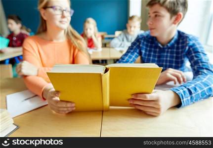 education, learning and people concept - high school students reading book on lesson together