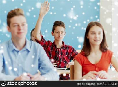 education, learning and people concept - student boy raising hand at school lesson over snow. student boy raising hand at school lesson