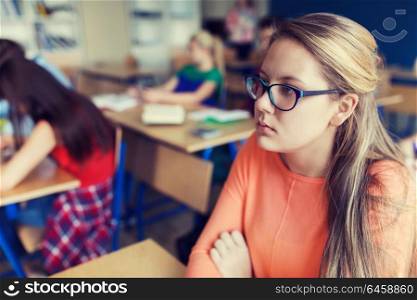 education, learning and people concept - student girl in eyeglasses at school lesson. student girl in eyeglasses at school lesson