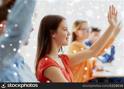 education, learning and people concept - student girl raising hand at school lesson over snow. student girl raising hand at school lesson