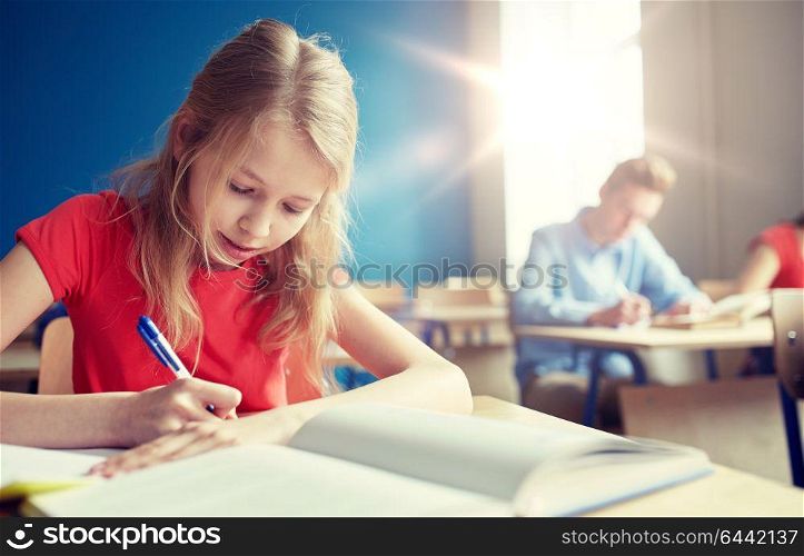 education, learning and people concept - student girl with book writing school test. student girl with book writing school test