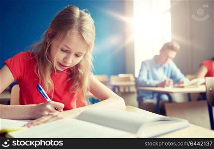 education, learning and people concept - student girl with book writing school test. student girl with book writing school test