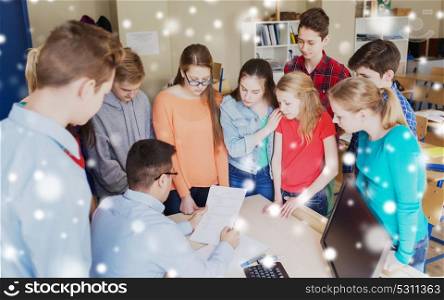 education, learning, teaching and people concept - group of students and teacher checking tests at school over snow. group of students and teacher with tests at school