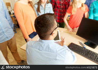 education, learning, teaching, technology and people concept - group of students and teacher with tablet pc and computer at school