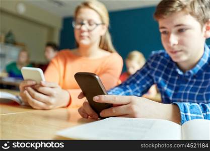 education, learning, technology, communication and people concept - high school students with smartphones texting on lesson