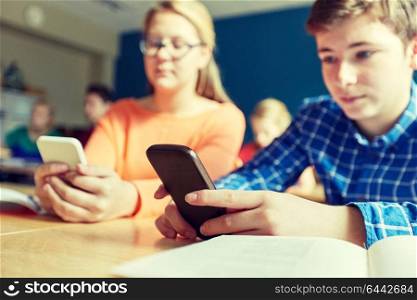 education, learning, technology, communication and people concept - high school students with smartphones texting on lesson. high school students with smartphones texting