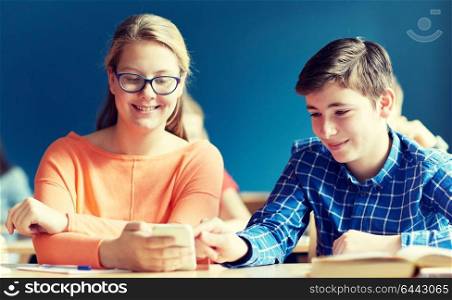 education, learning, technology, communication and people concept - students with smartphone texting at school lesson. students with smartphone texting at school