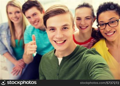 education, leisure and technology concept - five smiling students taking selfie at school