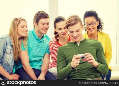 education, leisure and technology concept - five smiling students with digital camera at school