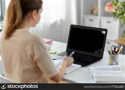 education, online school and distant learning concept - female student woman with laptop computer, notebook and book at home. student woman with laptop, notebook and book