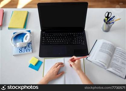 education, online school and distant learning concept - hands of student woman with laptop computer, notebook and book at home. hands of student with notebook and laptop on table