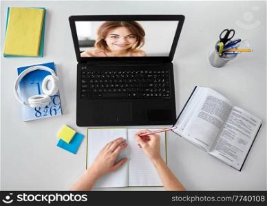 education, online school and distant learning concept - hands of student woman with teacher on laptop computer, notebook and book at home. hands of student with teacher on laptop screen