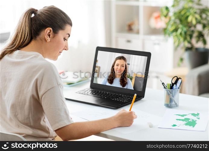 education, online school and distant learning concept - student woman having video call or meeting with teacher on laptop computer and drawing picture of cat on paper at home. woman having video call on laptop and drawing