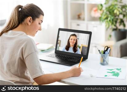 education, online school and distant learning concept - student woman having video call or meeting with teacher on laptop computer and drawing picture of cat on paper at home. woman having video call on laptop and drawing
