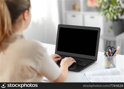 education, online school and distant learning concept - student woman with laptop computer and book typing at home. student woman with laptop and book at home