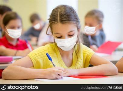 education, pandemic and health concept - group of students wearing face protective medical mask for protection from virus disease writing test at school. group of students in masks writing test at school