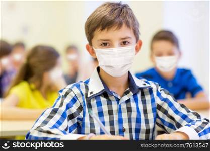 education, pandemic and health concept - student boy wearing face protective medical mask for protection from virus disease at school. student boy in protective medical mask at school
