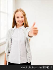 education, people and gesture concept - happy smiling student girl showing thumbs up at school. happy smiling student girl showing thumbs up