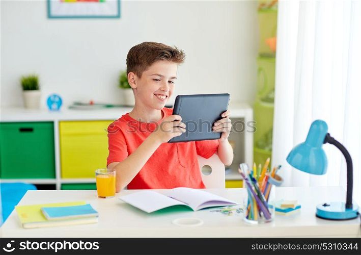 education, people and learning concept - happy student boy with tablet pc computer and notebook learning at home. student boy with tablet pc and notebook at home