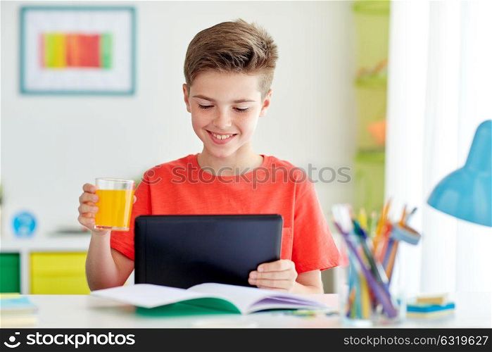 education, people and learning concept - happy student boy with tablet pc computer drinking orange juice at home. student boy with tablet pc and juice at home