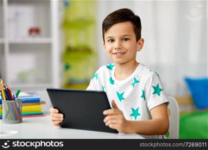 education, people and learning concept - happy student boy with tablet pc computer and notebook learning at home. student boy with tablet pc and notebook at home