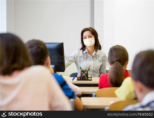 education, people and pandemic concept - group of children and teacher wearing face protective medical mask for protection from virus disease at school. teacher wearing face protective mask at school