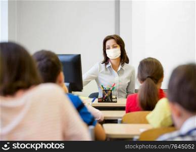 education, people and pandemic concept - group of children and teacher wearing face protective medical mask for protection from virus disease at school. teacher wearing face protective mask at school