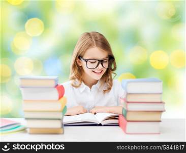 education, people, children and school concept - happy student girl in eyeglasses reading book over green lights background