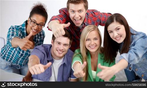 education, people, friendship and learning concept - group of happy international high school students or classmates showing thumbs up