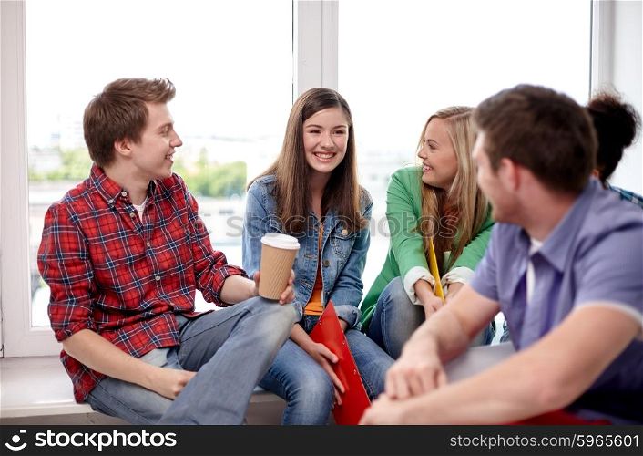 education, people, friendship, communication and learning concept - group of happy international high school students or classmates with folders and coffee talking