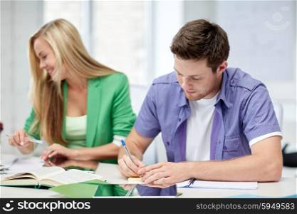 education, people, friendship, technology and learning concept - group of happy high school students or classmates with with textbooks and tablet pc computer learning in classroom
