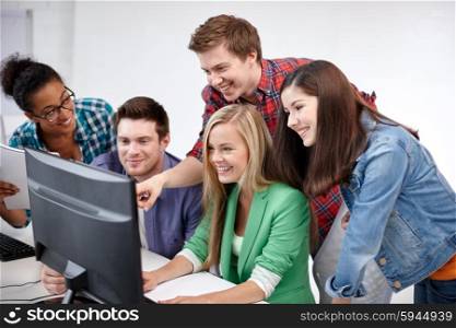 education, people, friendship, technology and learning concept - group of happy international high school students or classmates in computer class