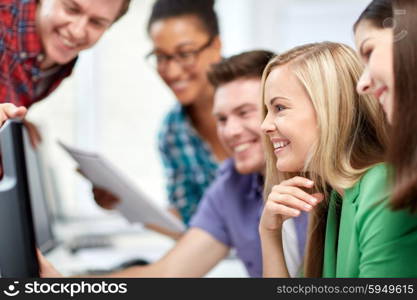 education, people, friendship, technology and learning concept - group of happy international high school students or classmates in computer class