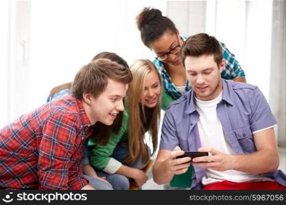 education, people, friendship, technology and learning concept - group of happy international high school students or classmates with smartphone in classroom